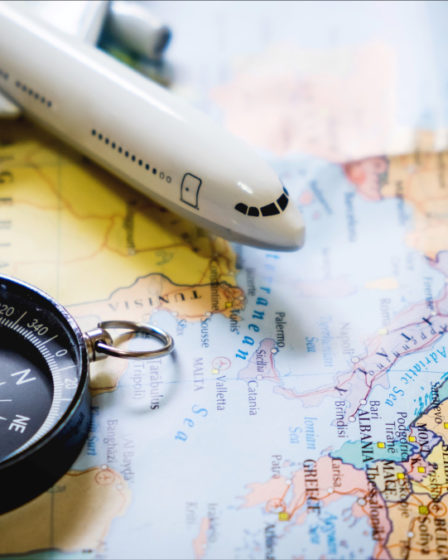 miniature tourist on compass over map with plastic toy airplane,abstract background to travel concept.