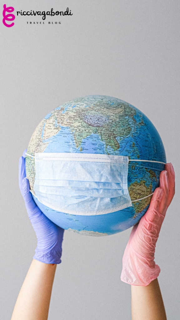 View of a globe with a medical mask hold by two hands with gloves