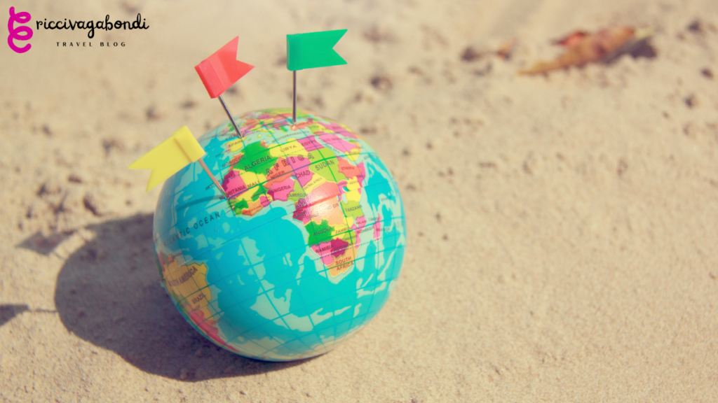 World map with flags on the sand on a sunny day