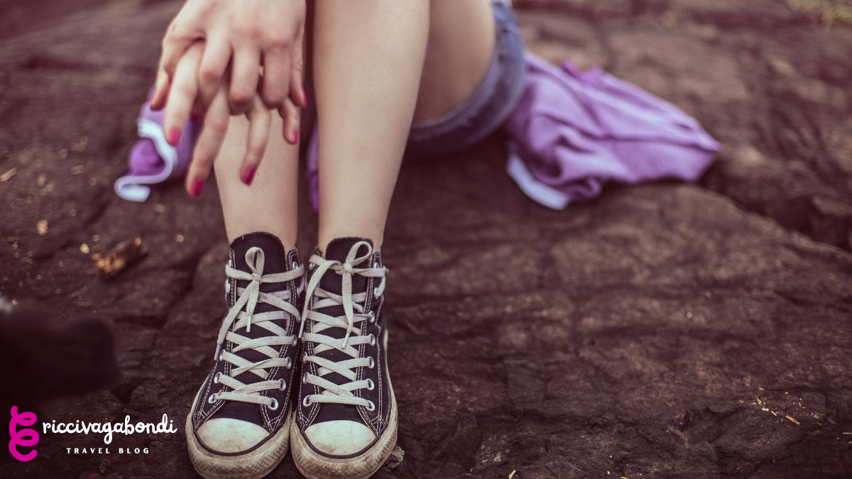 View of a young lady sitting on the ground with Converse on her feet
