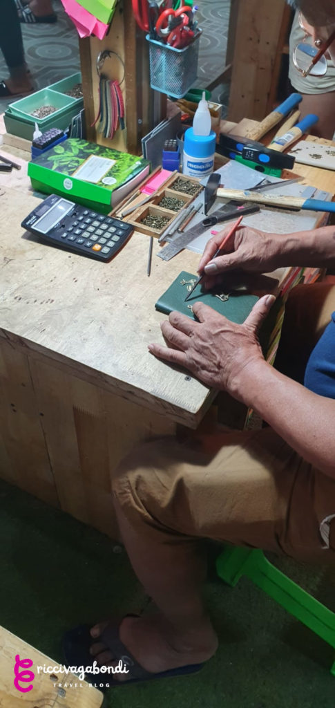 View of an artisan decorating a passport cover in a local Thai market